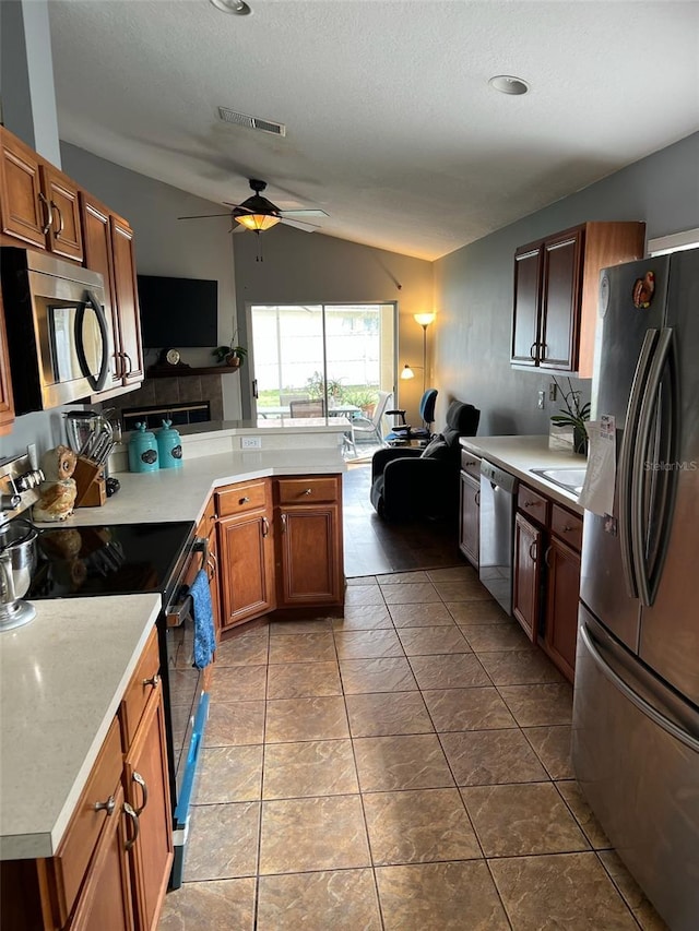 kitchen with open floor plan, light countertops, appliances with stainless steel finishes, and brown cabinetry