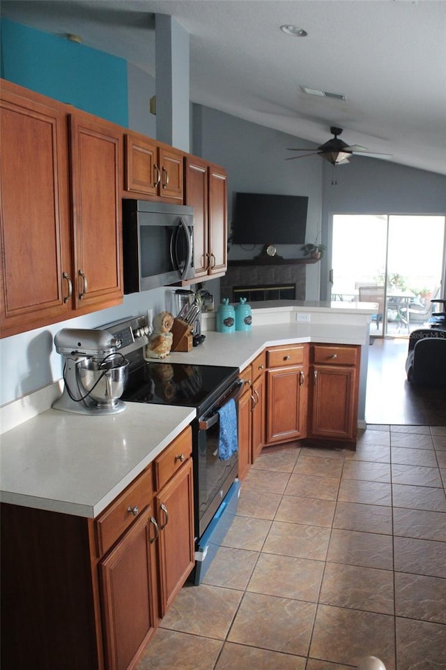 kitchen featuring brown cabinetry, open floor plan, vaulted ceiling, stainless steel appliances, and light countertops