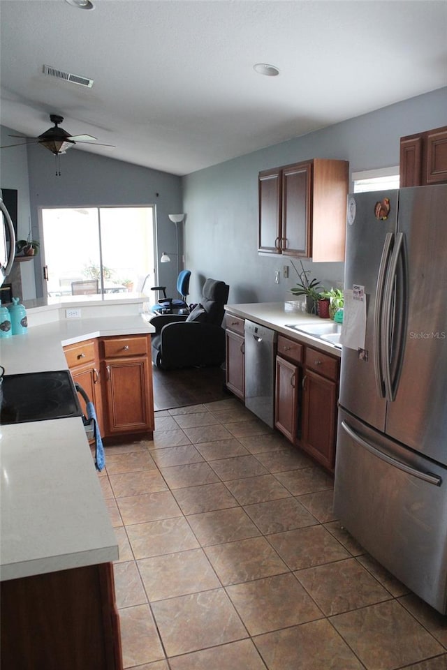 kitchen with light countertops, visible vents, appliances with stainless steel finishes, brown cabinetry, and open floor plan