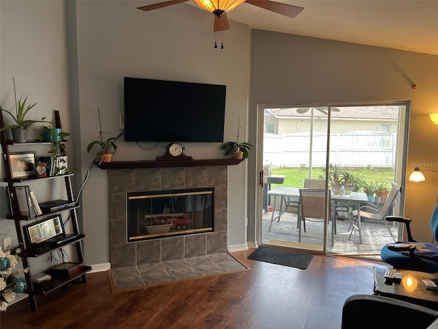 living room featuring a fireplace, a ceiling fan, vaulted ceiling, and wood finished floors