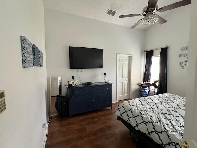 bedroom featuring dark wood-style flooring, lofted ceiling, visible vents, a ceiling fan, and a textured ceiling