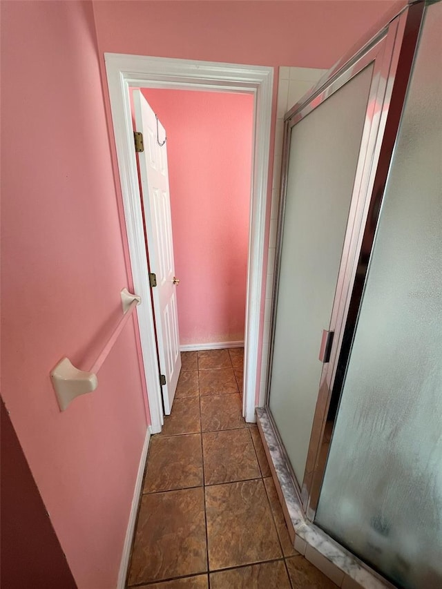 full bath with a stall shower, tile patterned flooring, and baseboards