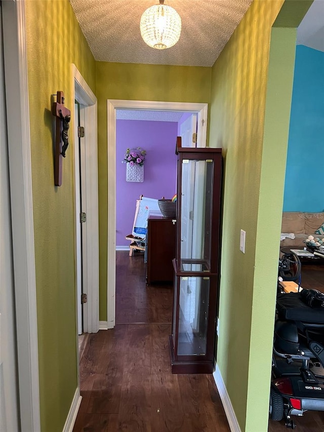 corridor with baseboards, dark wood finished floors, and a textured ceiling