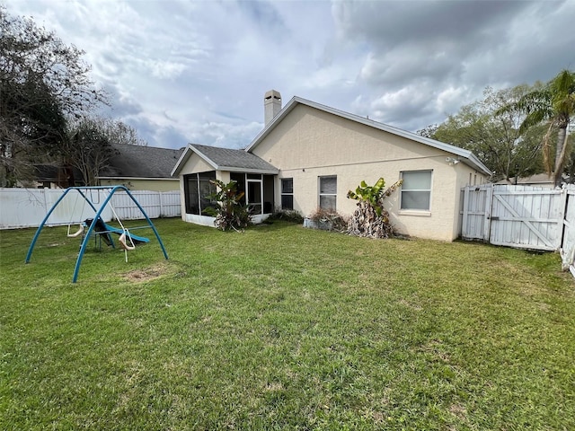 back of property featuring a lawn, a fenced backyard, a sunroom, and stucco siding