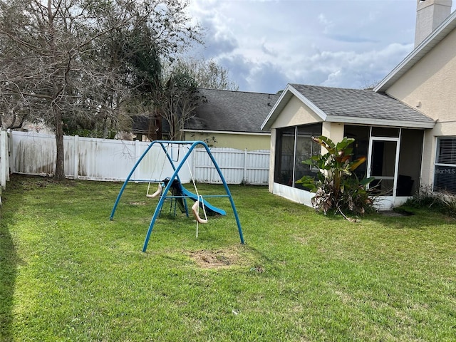 view of jungle gym with a lawn, a fenced backyard, and a sunroom