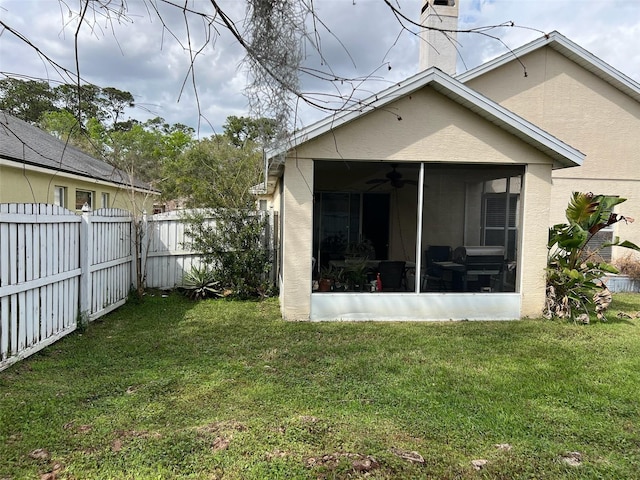 back of house with a sunroom, a fenced backyard, stucco siding, and a yard