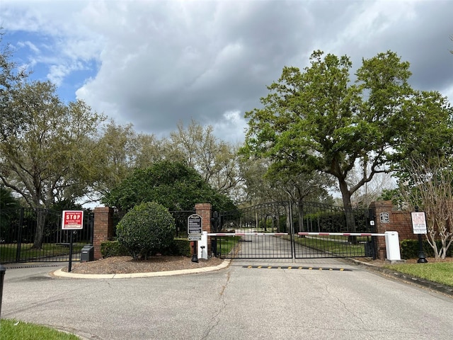 view of street with traffic signs, a gate, curbs, and a gated entry