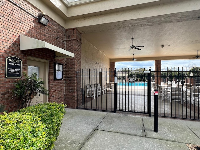 view of gate featuring a community pool, fence, and a ceiling fan