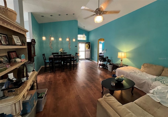 living room featuring dark wood-style floors, arched walkways, ceiling fan, high vaulted ceiling, and baseboards