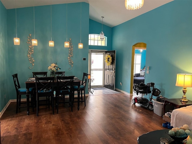 dining space featuring high vaulted ceiling, baseboards, arched walkways, and dark wood-style flooring