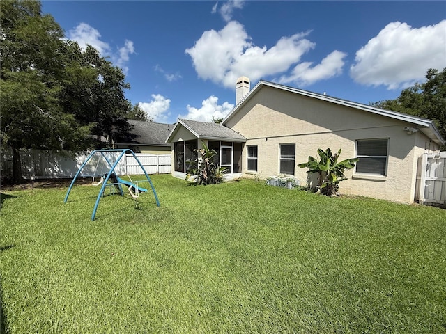 536 Dunoon St, Ocoee, FL 34761 - back of house with a playground, a fenced backyard, a sunroom, a chimney, and stucco siding
