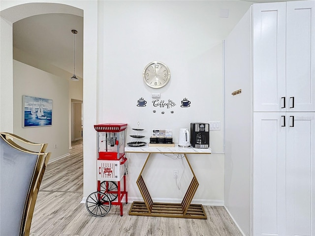 interior space featuring arched walkways, light wood finished floors, and baseboards