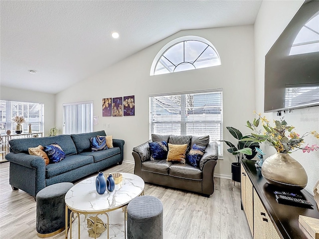 living area featuring a textured ceiling, high vaulted ceiling, light wood-style flooring, and baseboards