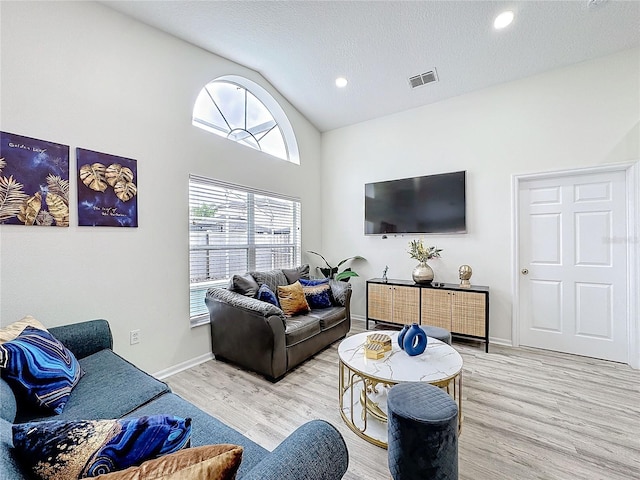 living room with visible vents, vaulted ceiling, a textured ceiling, and wood finished floors