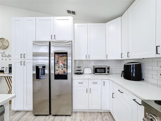 kitchen with appliances with stainless steel finishes, white cabinets, visible vents, and light wood-style floors