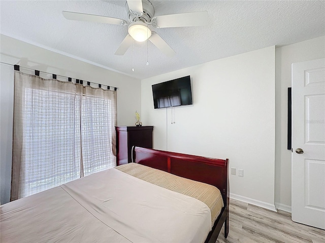 bedroom with a textured ceiling, light wood finished floors, and a ceiling fan