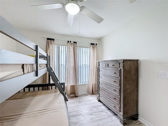 bedroom with light wood-style floors, a ceiling fan, baseboards, and a textured ceiling