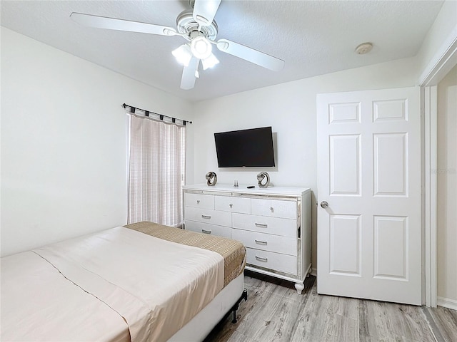 bedroom with light wood-style floors, a textured ceiling, and a ceiling fan