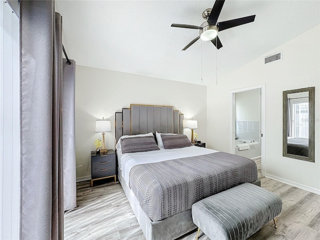 bedroom featuring visible vents, baseboards, connected bathroom, light wood-style flooring, and vaulted ceiling