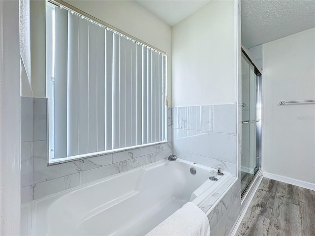 full bath with a textured ceiling, a stall shower, wood finished floors, and a bath