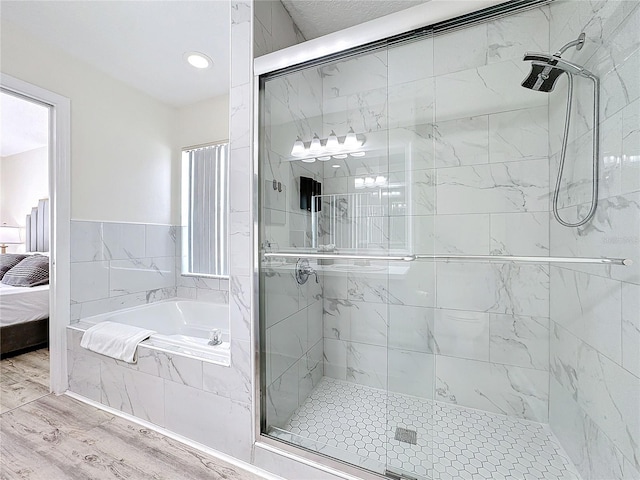 ensuite bathroom with a garden tub, a shower stall, and wood finished floors