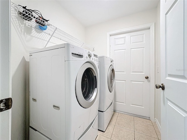 clothes washing area featuring laundry area, separate washer and dryer, and light tile patterned flooring