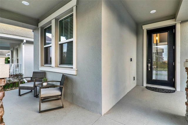 property entrance with a porch and stucco siding