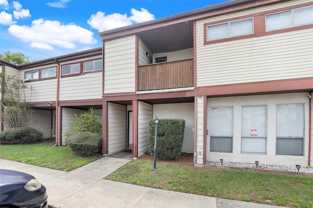 multi unit property featuring a front yard and a balcony