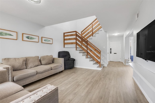 living area featuring baseboards, stairway, visible vents, and light wood-style floors