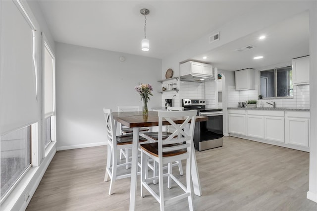 dining space with light wood-style floors, baseboards, and visible vents