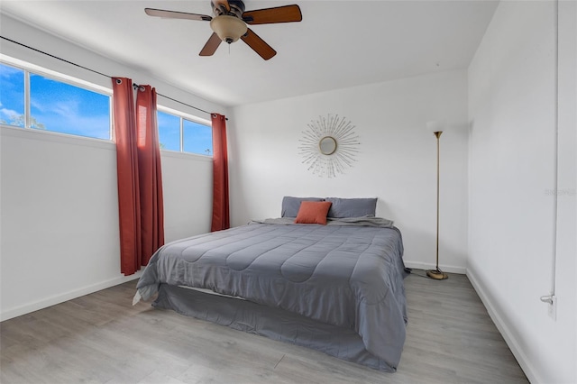 bedroom with light wood-style floors, ceiling fan, and baseboards