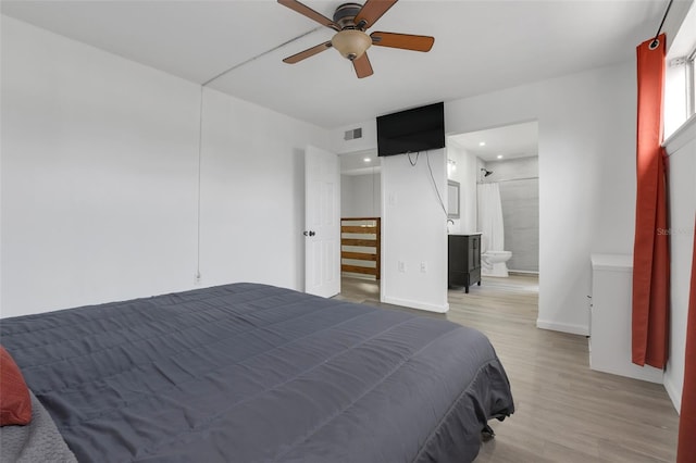 bedroom featuring visible vents, light wood-style floors, a ceiling fan, ensuite bath, and baseboards