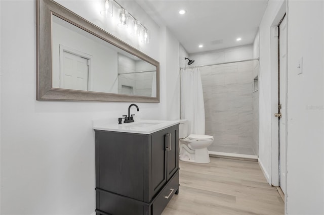 full bath with toilet, wood finished floors, vanity, a shower stall, and recessed lighting