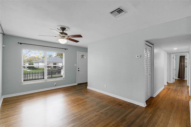 unfurnished room featuring dark wood-type flooring, visible vents, baseboards, and a ceiling fan