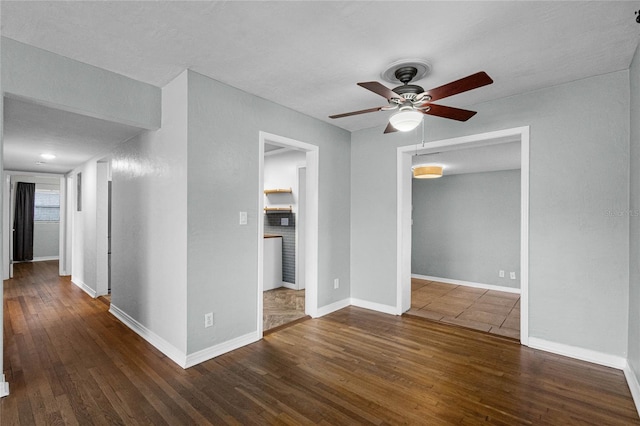 unfurnished room featuring dark wood-style floors, ceiling fan, and baseboards