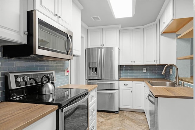 kitchen featuring butcher block counters, visible vents, appliances with stainless steel finishes, white cabinets, and a sink