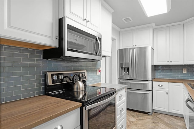 kitchen featuring stainless steel appliances, tasteful backsplash, butcher block countertops, and white cabinetry