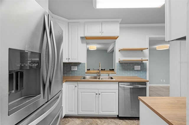 kitchen with appliances with stainless steel finishes, a sink, and white cabinetry