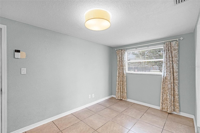 unfurnished room featuring light tile patterned flooring, a textured ceiling, and baseboards