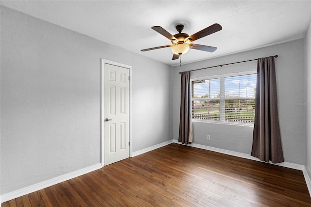 empty room featuring ceiling fan, dark wood-style flooring, and baseboards