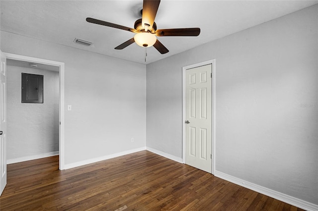 spare room with electric panel, baseboards, visible vents, dark wood finished floors, and ceiling fan