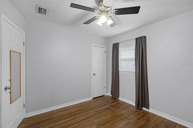 empty room featuring dark wood-style floors, visible vents, baseboards, and a ceiling fan