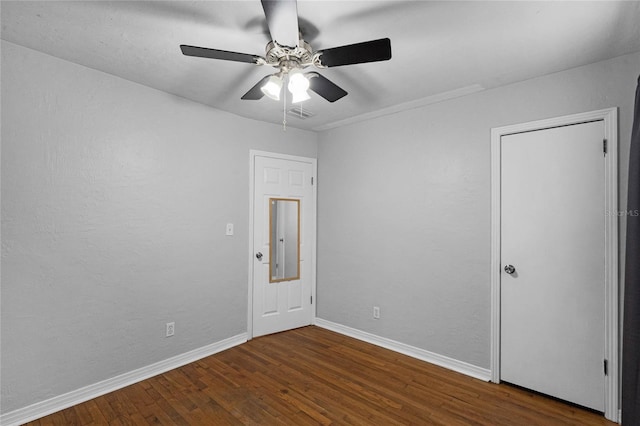 spare room featuring a ceiling fan, dark wood finished floors, and baseboards