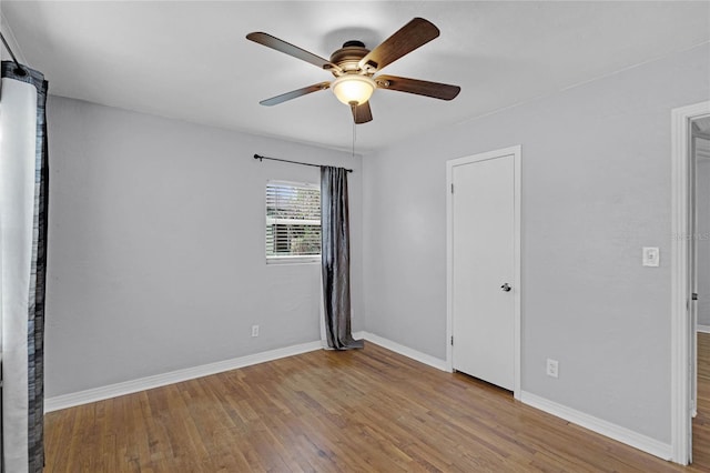 spare room with ceiling fan, light wood-style flooring, and baseboards