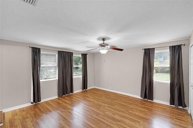 spare room with light wood-type flooring, visible vents, and baseboards