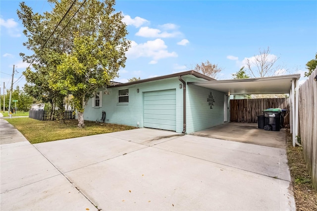 view of home's exterior featuring concrete driveway, an attached carport, an attached garage, and fence