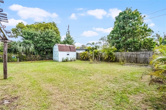 view of yard with a fenced backyard, a storage unit, and an outbuilding