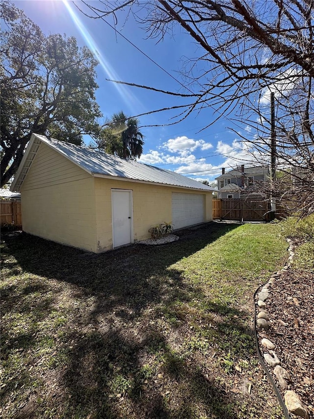 view of side of home featuring an outbuilding, metal roof, a lawn, and fence