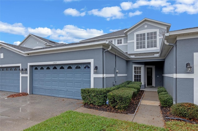 townhome / multi-family property featuring a garage, driveway, and stucco siding