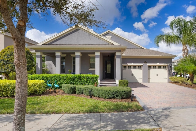 greek revival inspired property featuring decorative driveway, an attached garage, and stucco siding